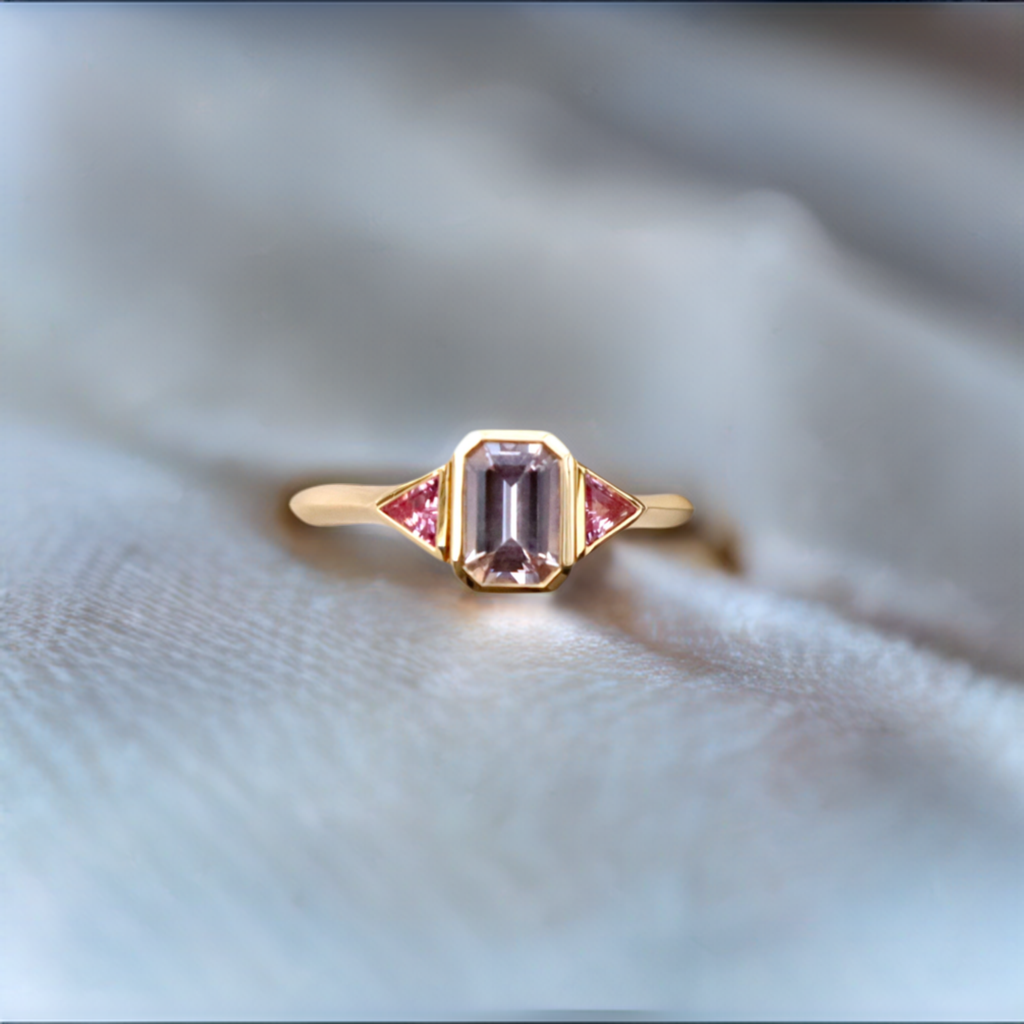 custom designed ring in 18k yellow gold with a emerald shaped purple sapphire and pink sapphire side stones